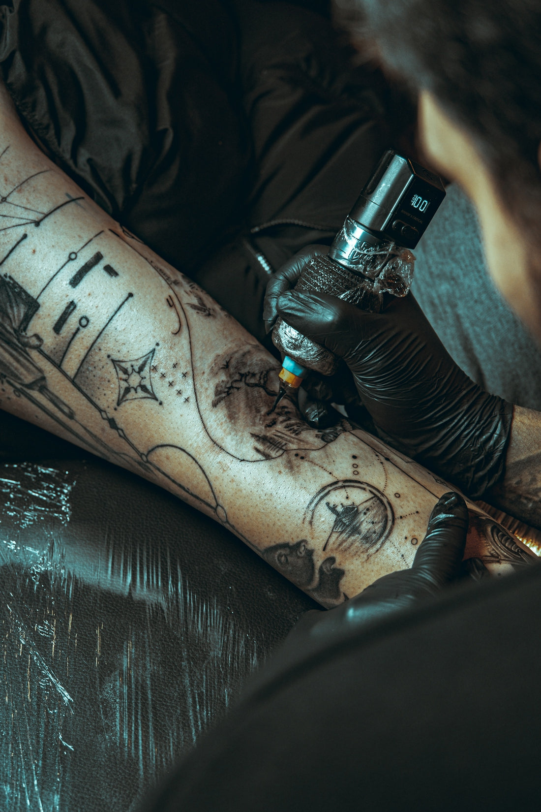 Tattoo artist applying ink to a client's leg